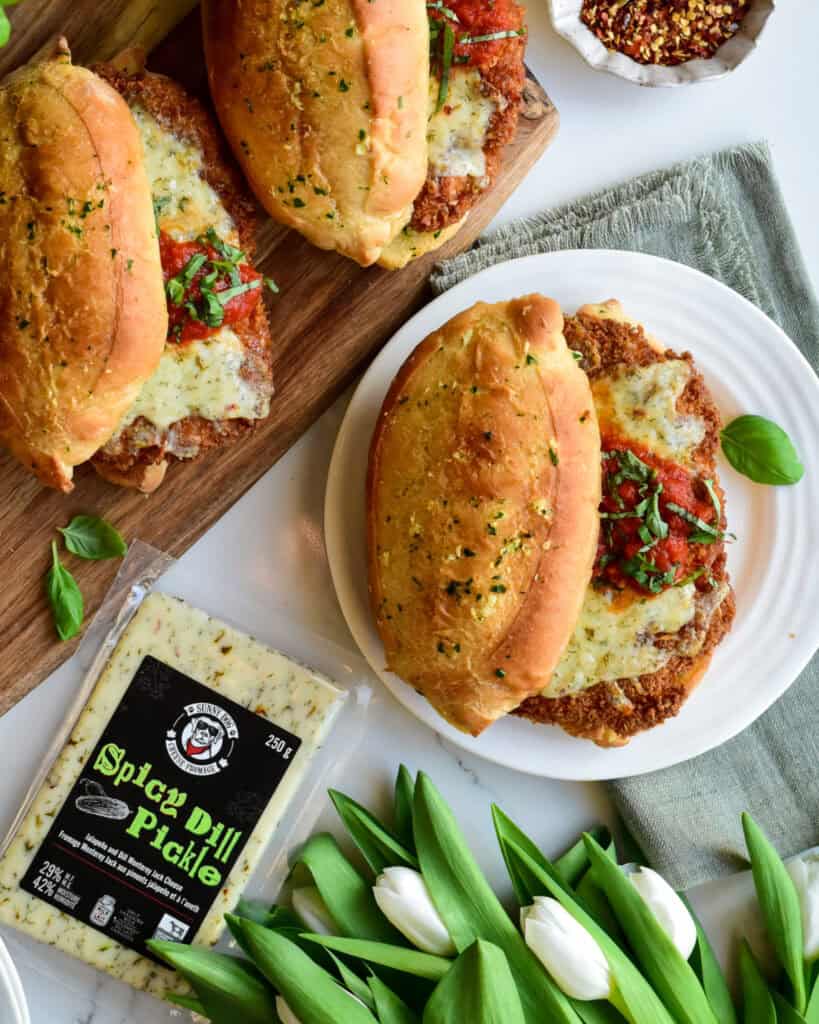 A close up of a crispy chicken sandwich with melted cheese, tomato sauce and basil.