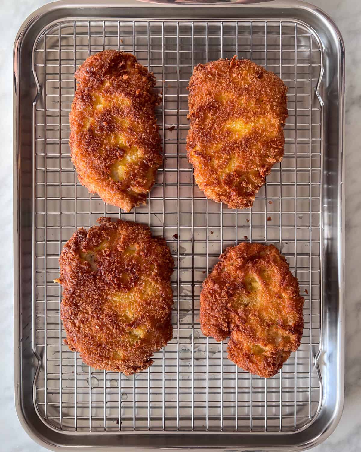 Four pieces of golden brown crispy chicken on a rack.