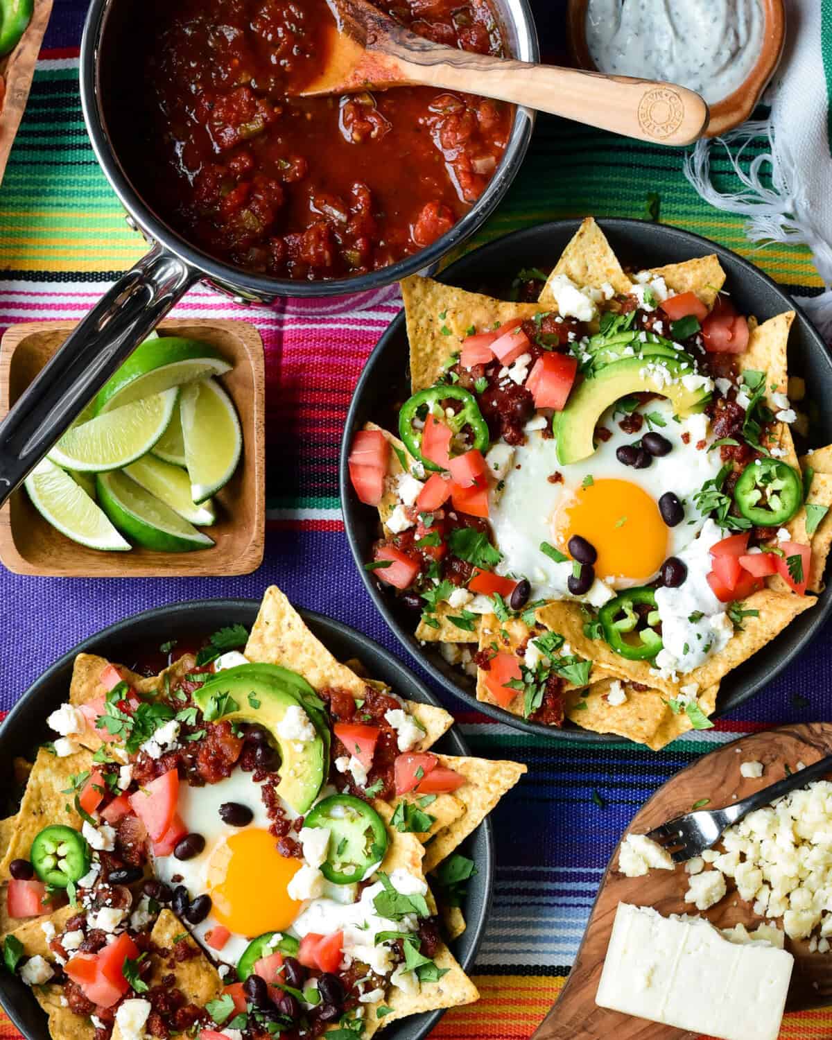 Two chilaquiles breakfast bowls with a sunny side up egg and other colourful toppings.