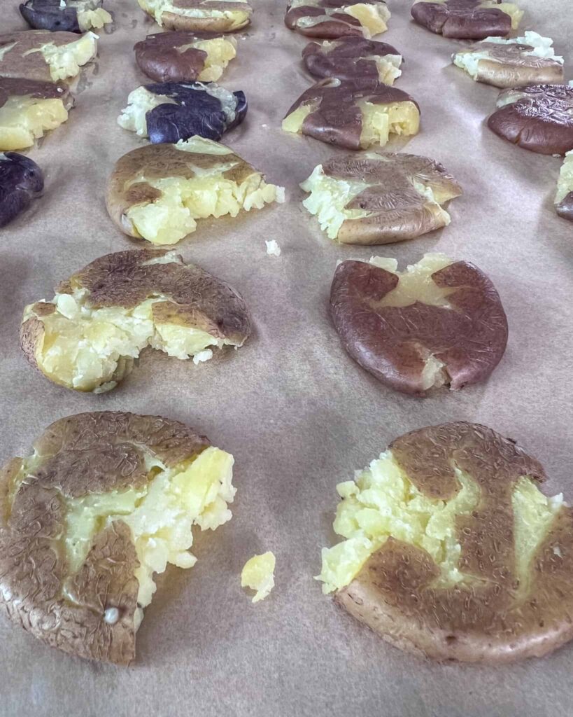 A side view of smashed potatoes that are ready to go in the oven.