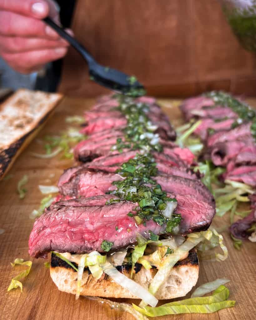 Building a grilled steak sandwich with chimichurri.