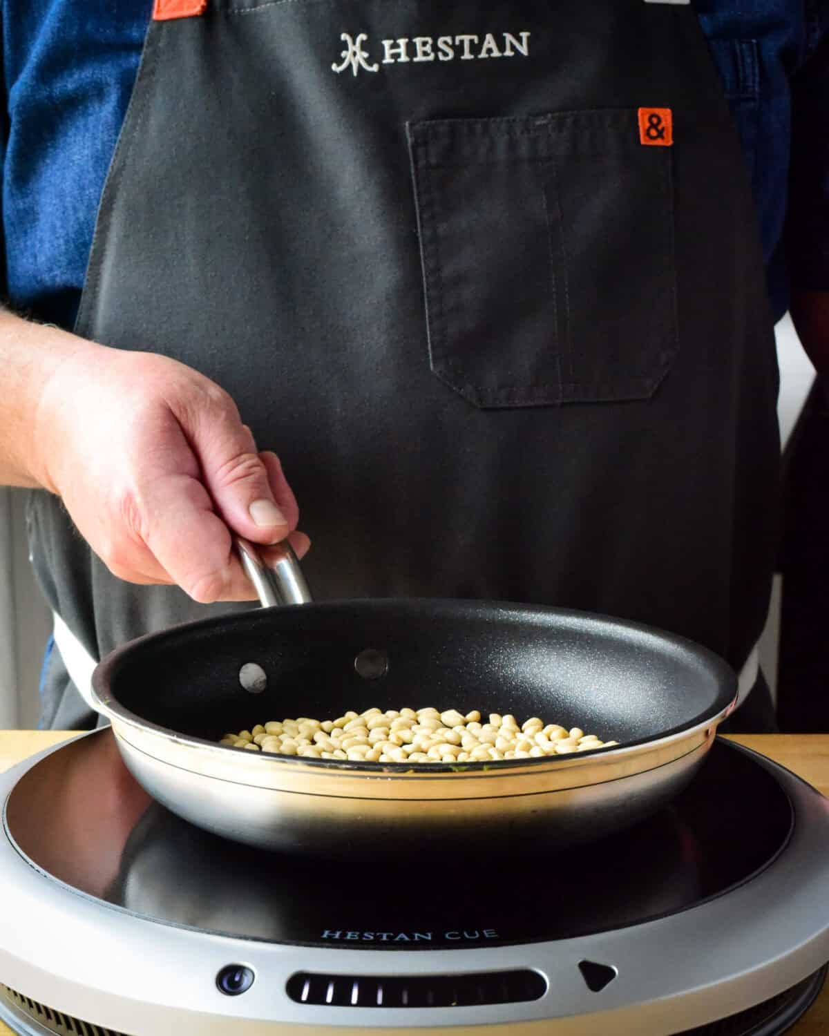 Toasting pine nuts in a skillet.