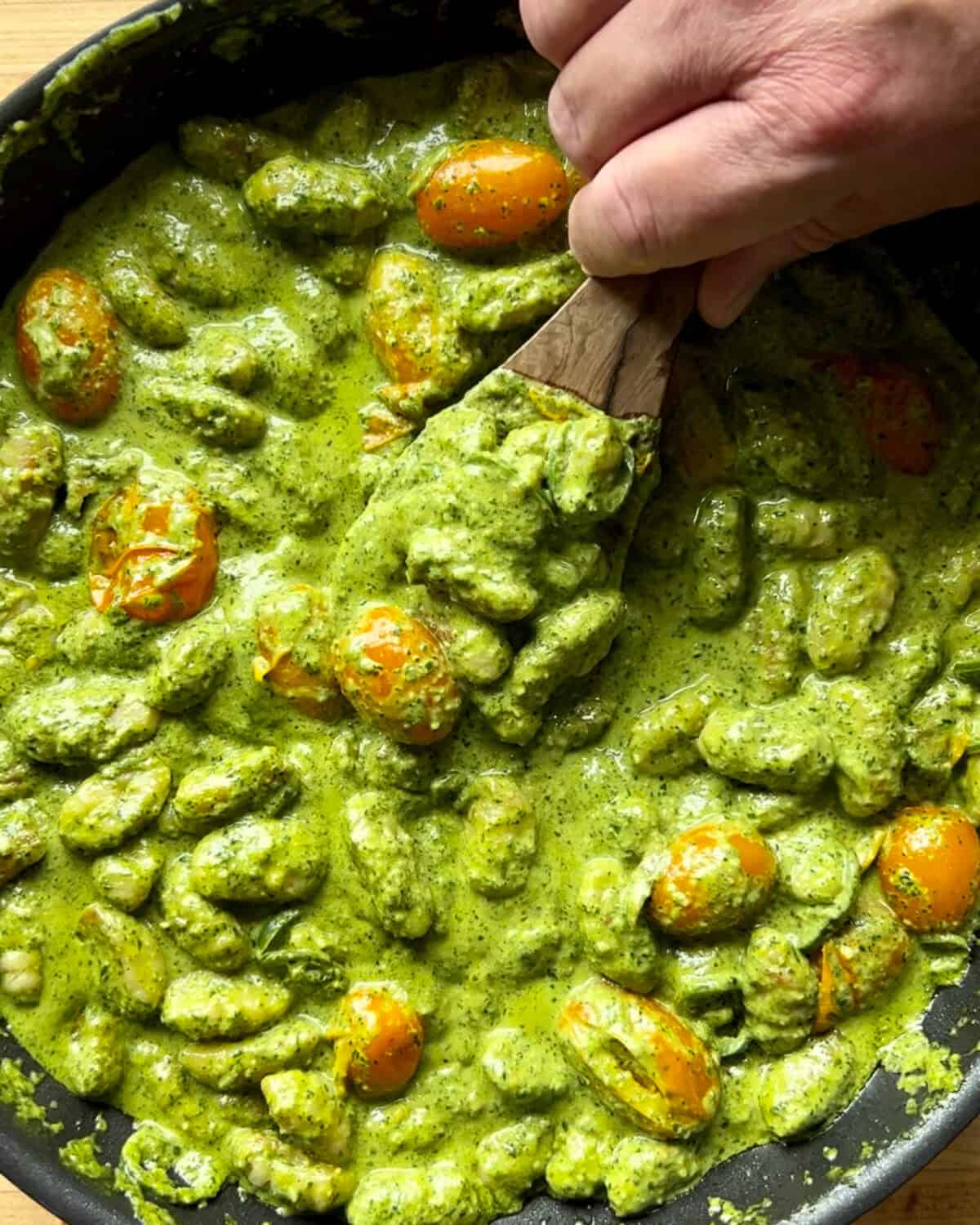Stirring the pesto and tomato gnocchi.
