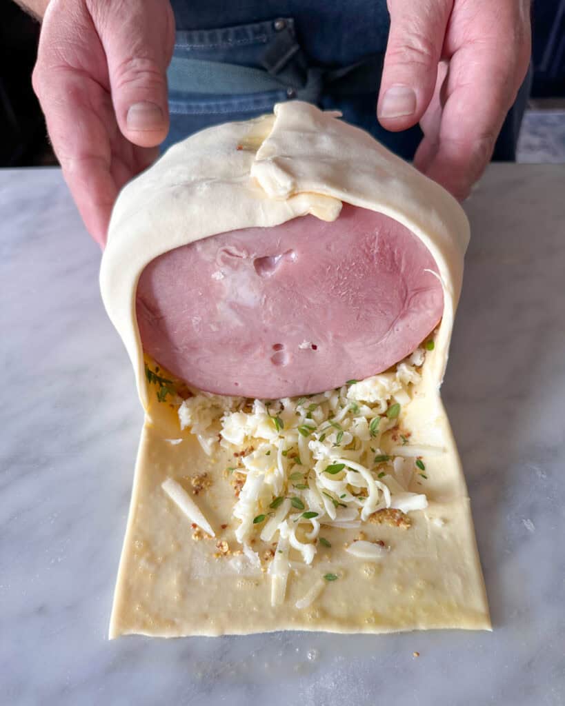 Fold the pastry over the ham, using more egg wash if necessary to secure each fold.