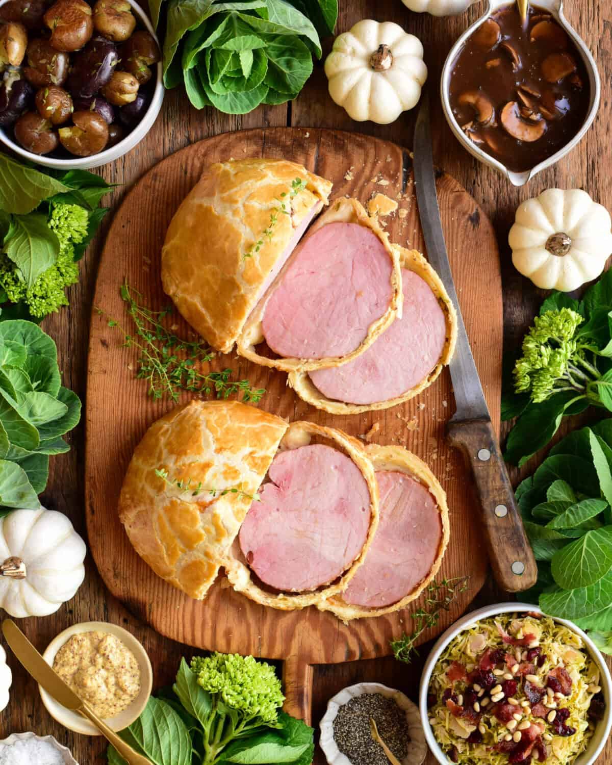 Two sliced ham wellingtons served with Marsala Mushroom Sauce, Shredded Brussels Sprouts with Pine Nuts and Pancetta, and smashed potatoes with thyme.