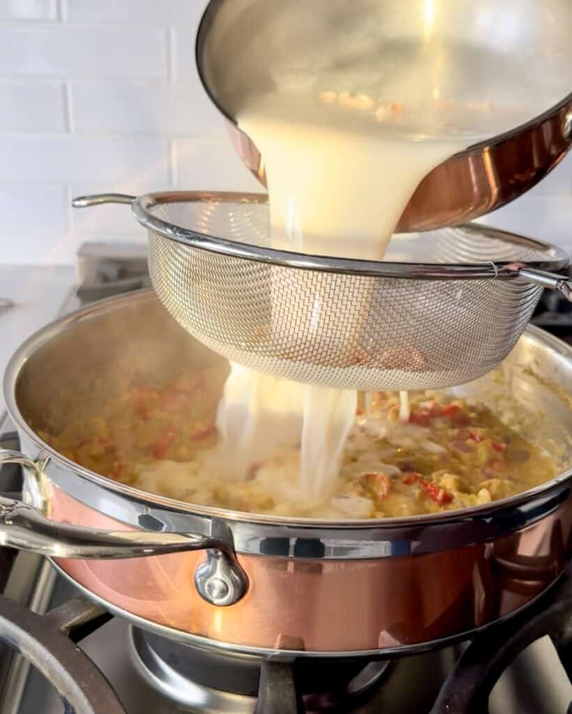 Pour the stock and coconut milk, a little at a time, through a mesh strainer to remove the shrimp shells.