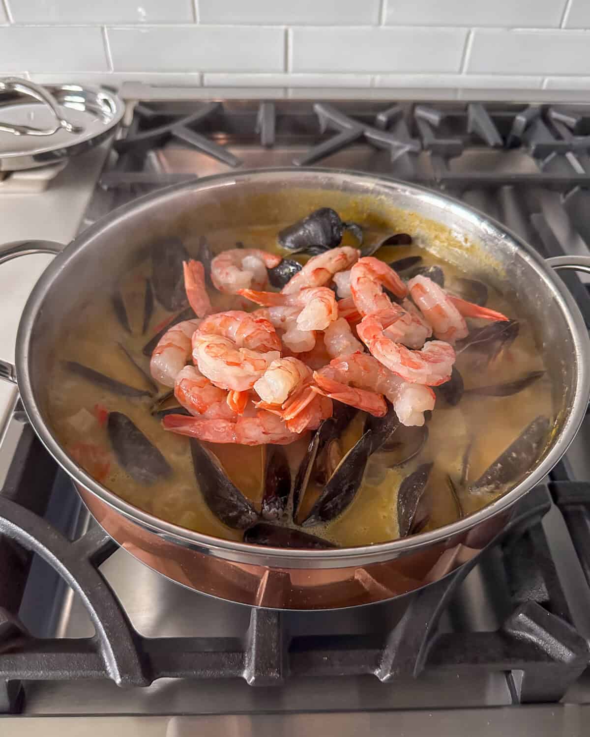 Adding the mussels and shrimp into the yellow curry.