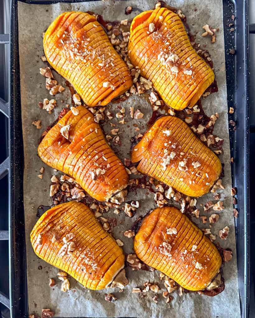 Six hasselback honeynut squash on a sheet pan.