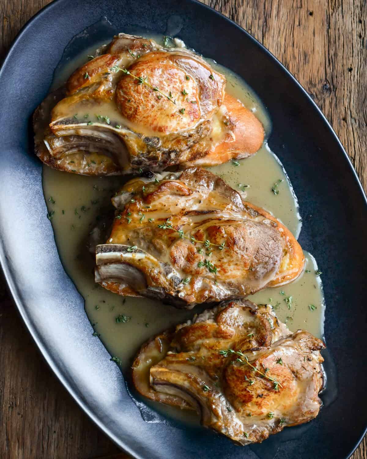 A top down image of oven baked French onion pork chops with gravy poured on over top.