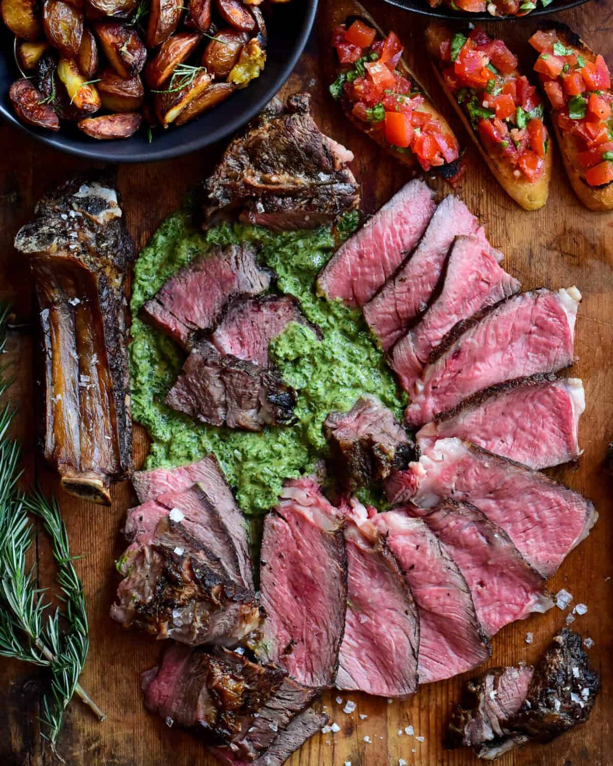 Florentine-Style Steak served with salsa verde, crispy potatoes (cooked in the beef fat trimmings) and bruschetta.