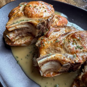 Thick cut and stuffed pork chops are placed on the toast and gravy is poured overtop.