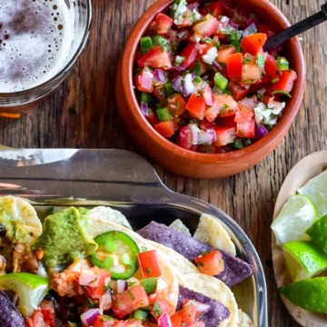 A bowl of Pico de Gallo beside a tray of nachos.