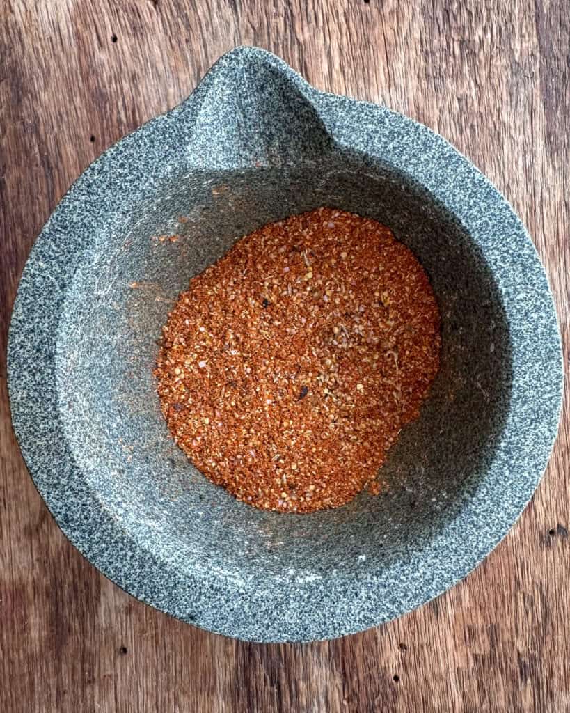 A mortar and pestle with ground spices for a Spanish steak sauce.
