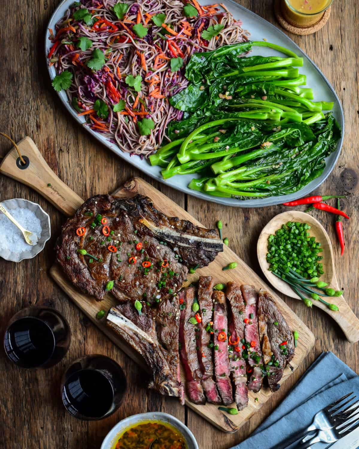 Two Grilled Ribeye Steaks served with an Asian-Inspired sauce, griddled veggies, and a refreshing soba noodle-slaw, each tossed in a zesty vegetable ginger dressing.
