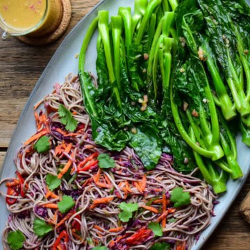 A Soba Noodle-Slaw and griddled Chinese Broccoli on a platter with a jar of ginger dressing.
