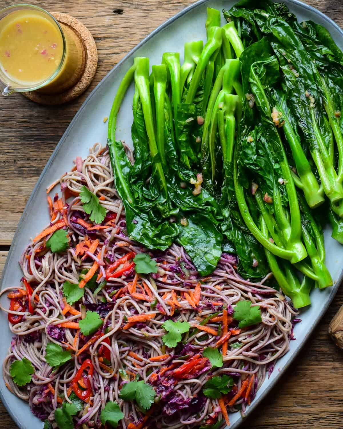 A Soba Noodle-Slaw and griddled Chinese Broccoli on a platter with a jar of ginger dressing.