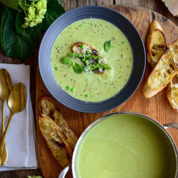 A pot and bowl of Spring Pea and Asparagus Soup served with baguette toasts.