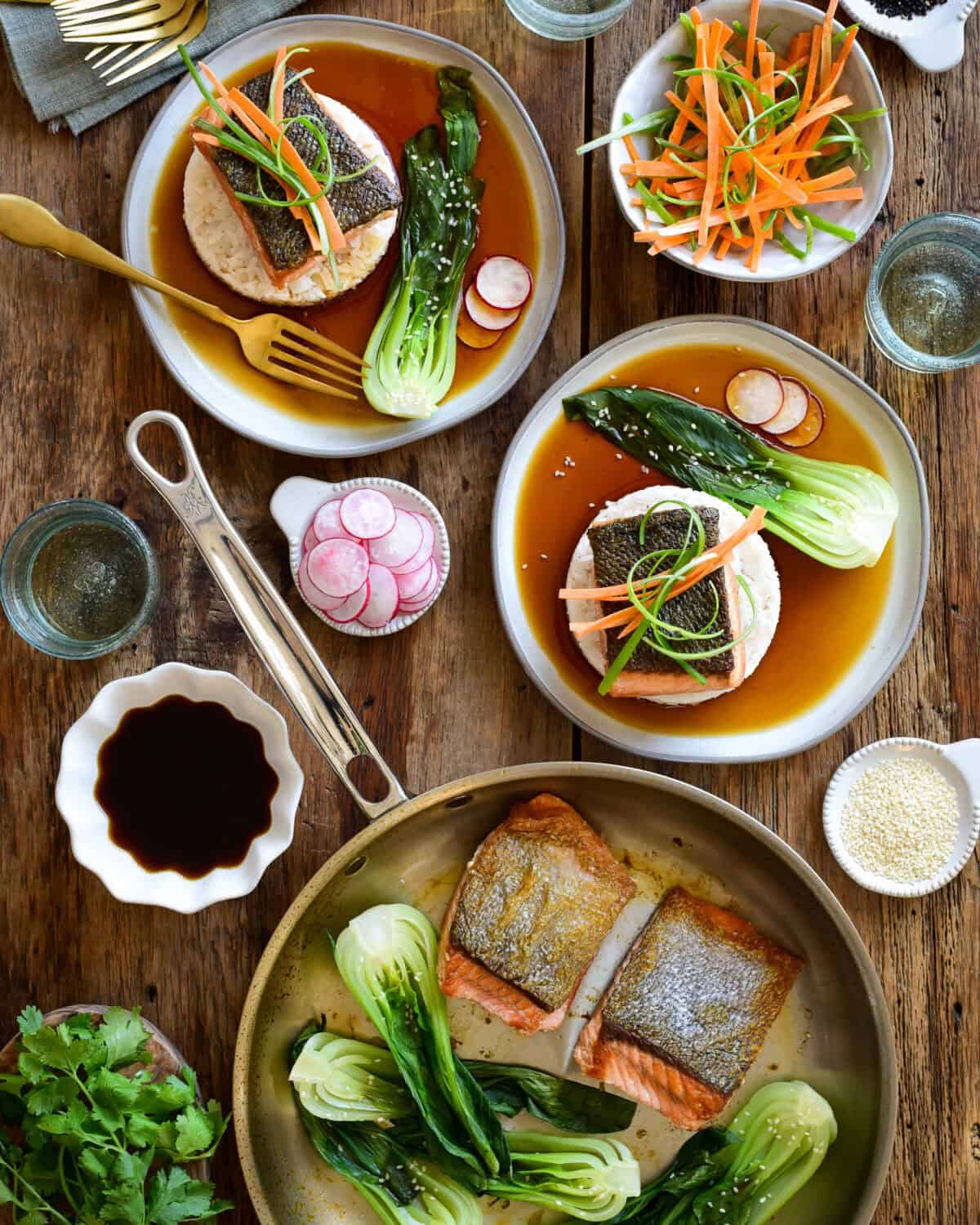 Salmon with Ponzu Sauce served on two plates with rice and bok choy served with fresh vegetable garnishes.