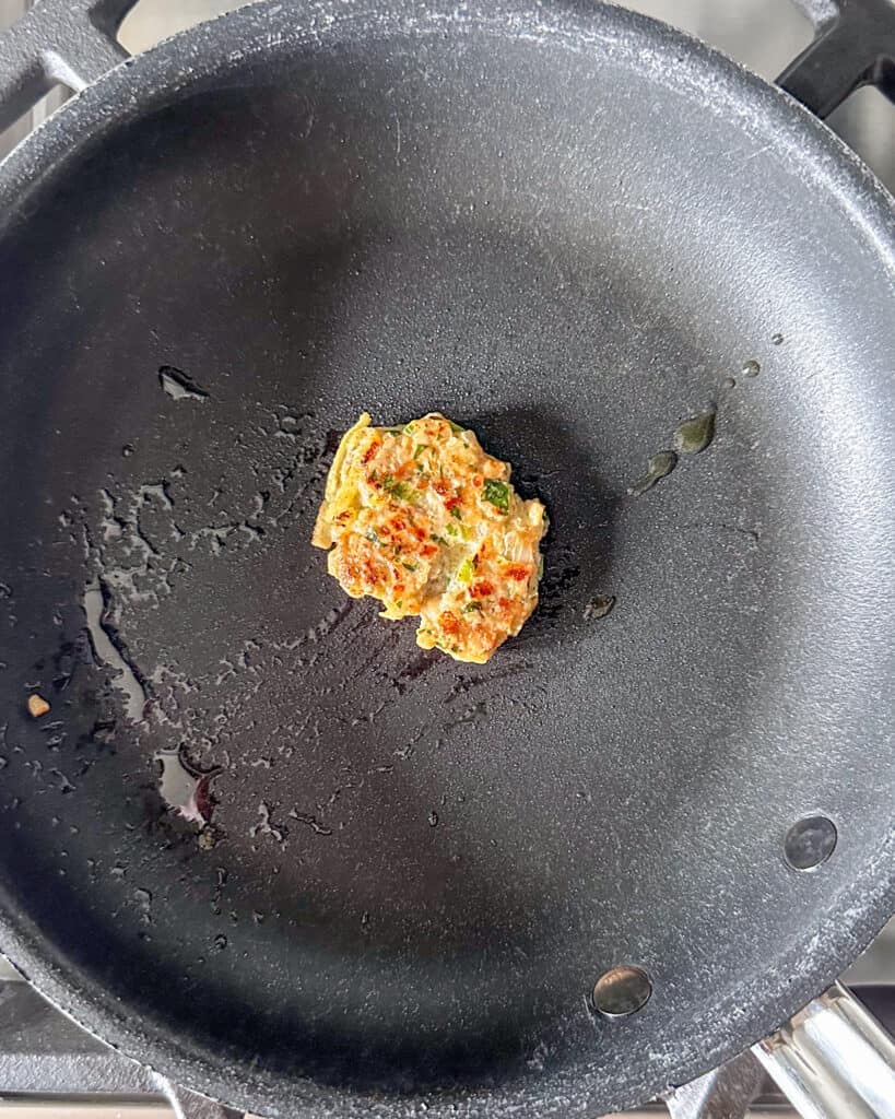 A small test cooked patty of the pork mixture in pan.