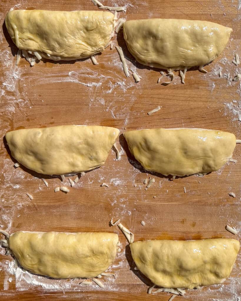 Six cresent shaped pizza dough.