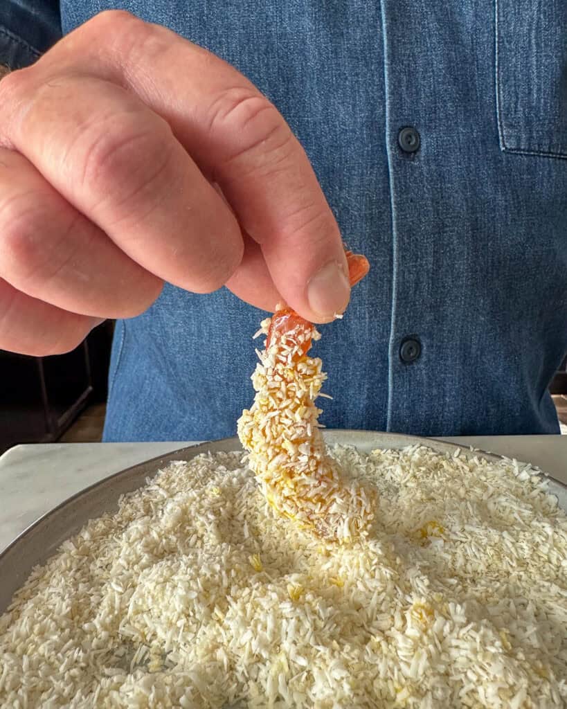 Coating the shrimp in the coconut-panko mixture.