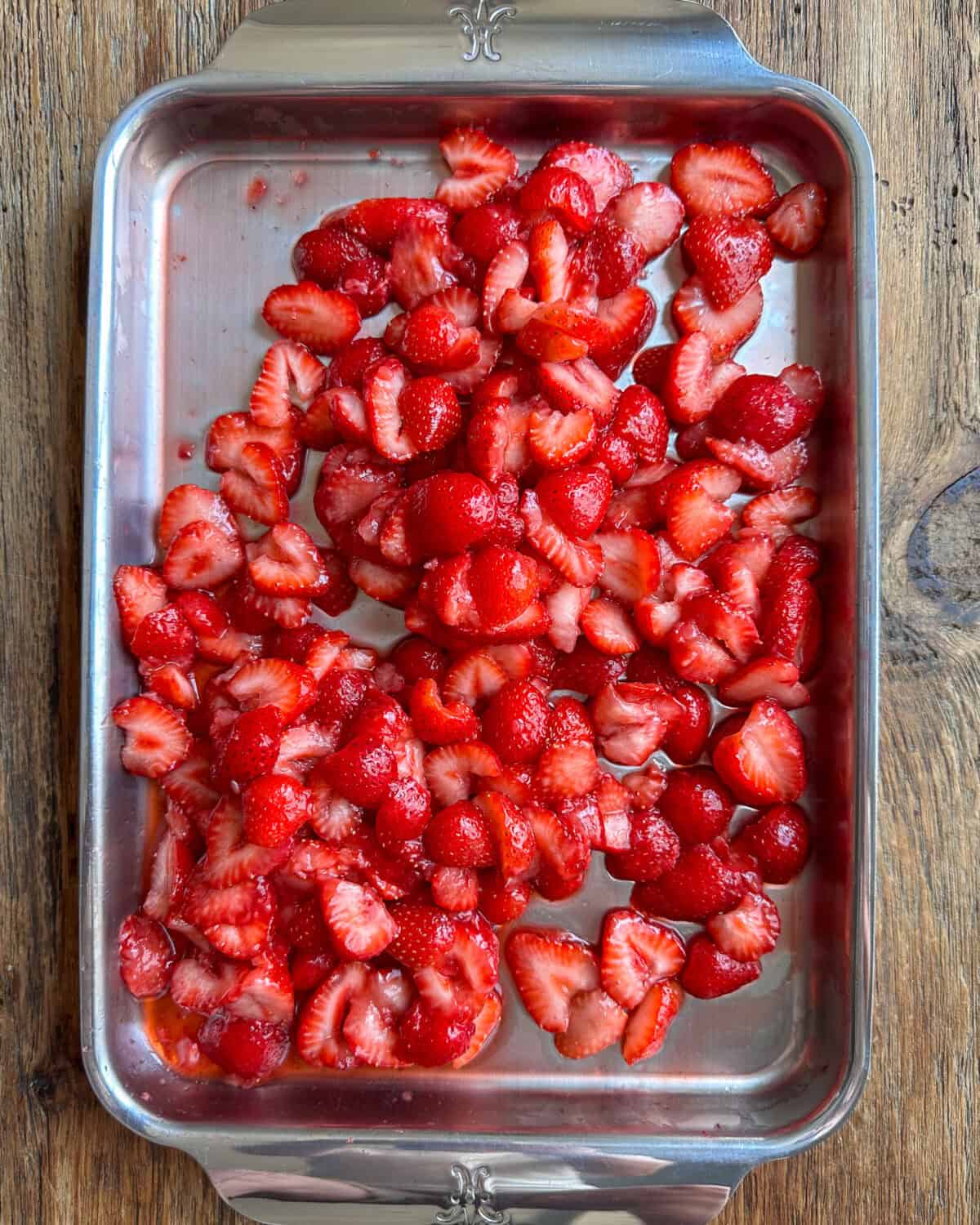 A sheet pan of hulled and sliced strawberries.