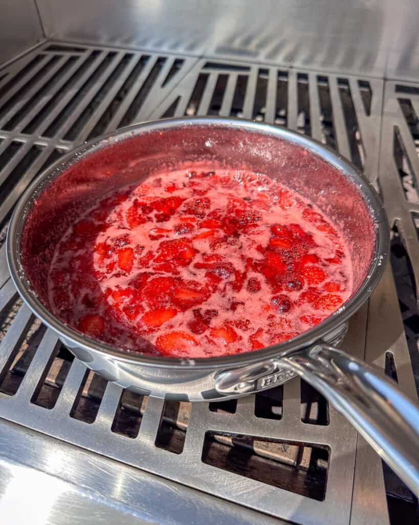 A saucepan with strawberry and ginger jam that has boiled.