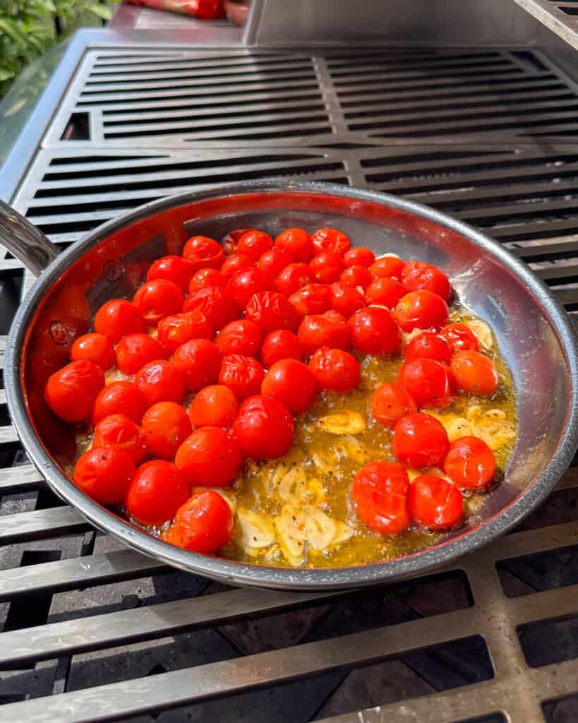 Blistering tomatoes on a skillet on the grill.