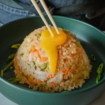 A confit egg yolk dripping down a mound of Japanese Shrimp & Egg Fried Rice.