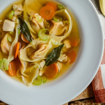 A bowl of turkey soup with squash wontons.