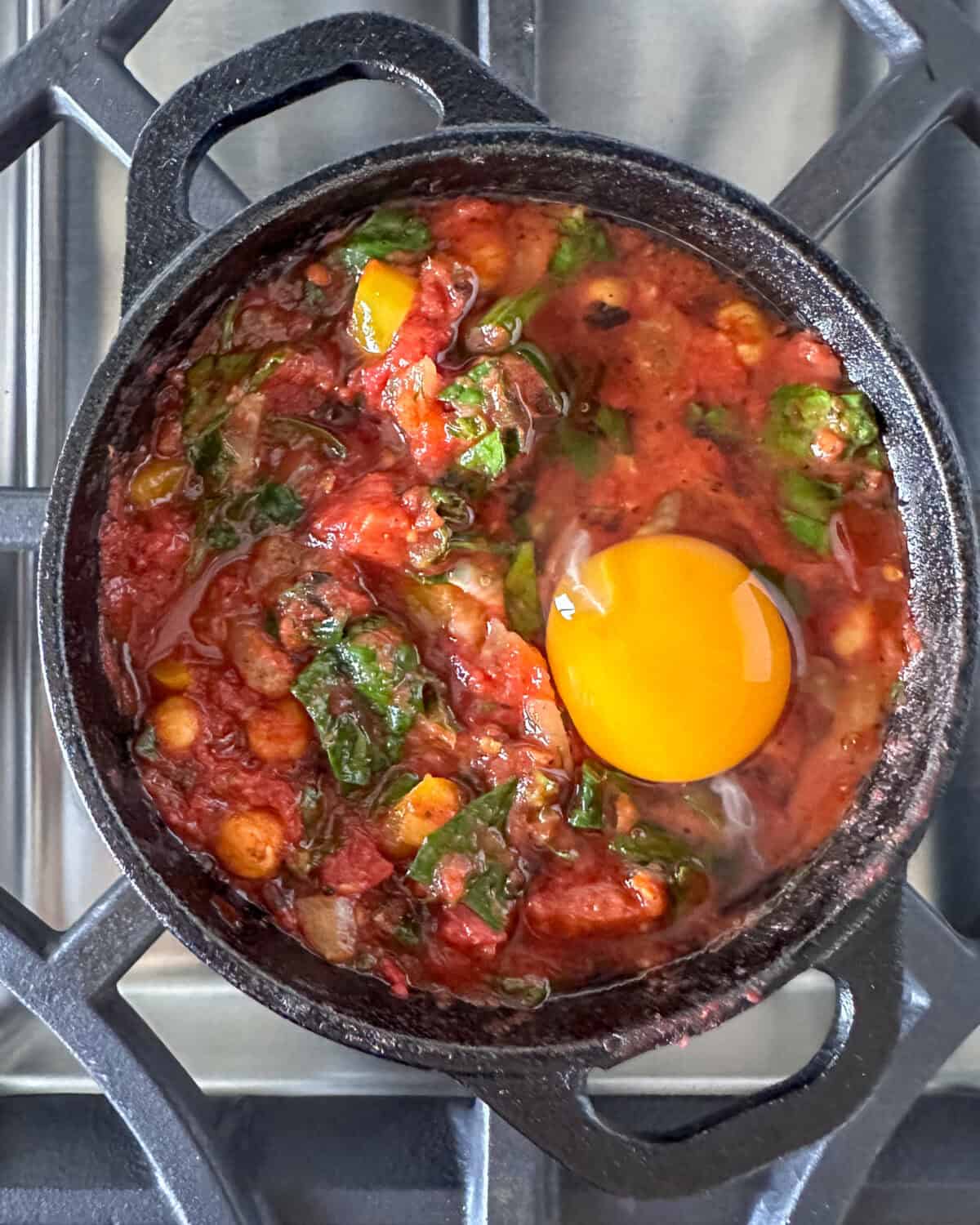 An egg in an individual shackshuka ready to be baked.