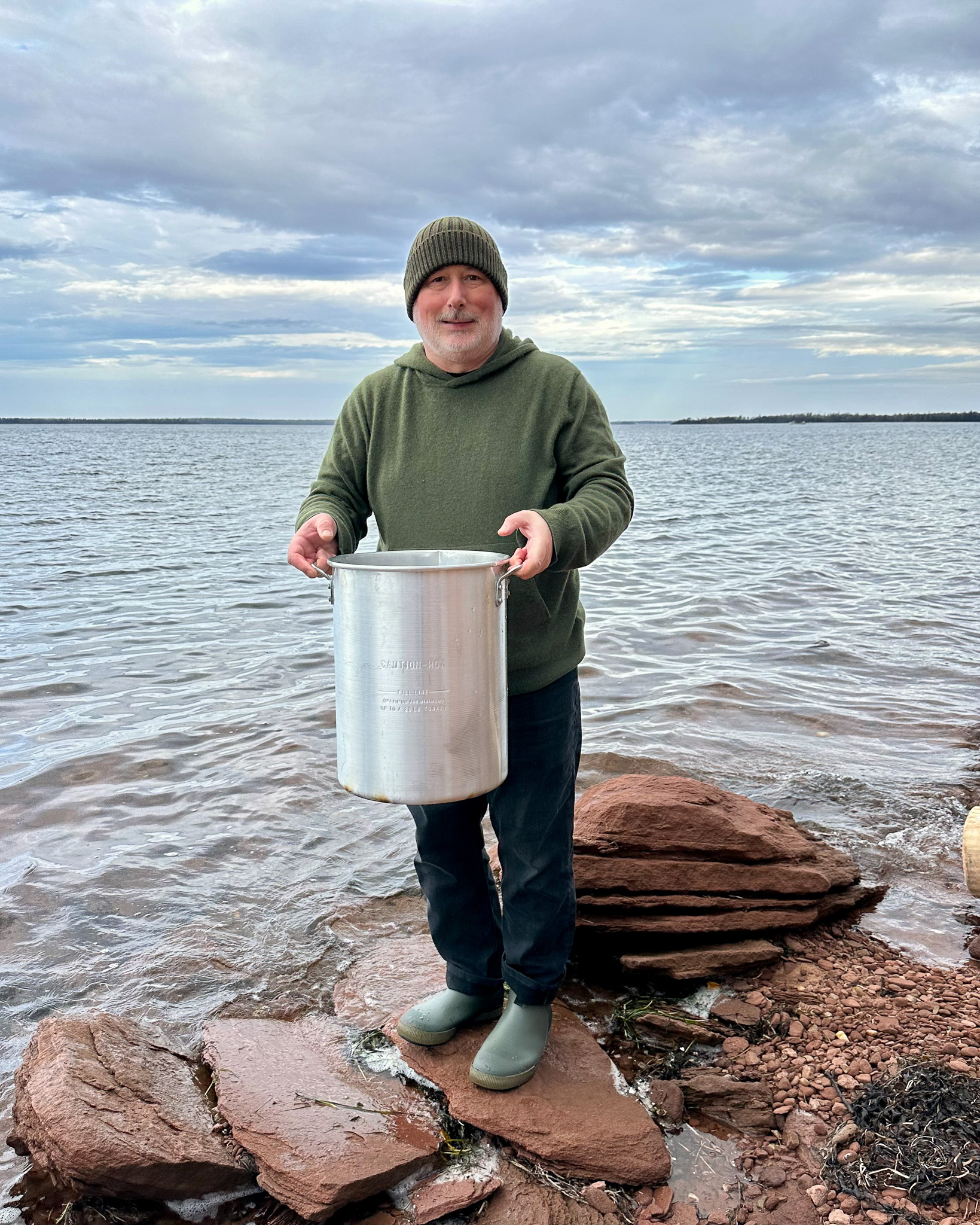 Zimmy holding a seafood pot filled with salt water on the shores of PEI.