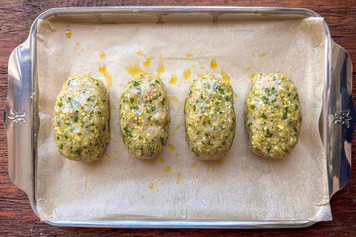 Divide the turkey mixture into four equal portions and shape each into oval turkey meatloaves. Place the loaves on the prepared baking sheet. Drizzle with olive oil and use a pastry brush to coat the surface of each loaf evenly.