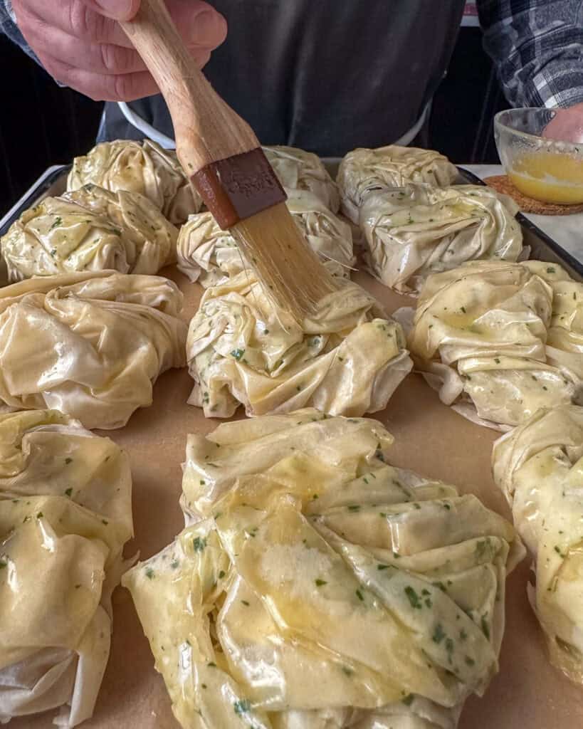 Brush the phyllo parsels with melted butter.