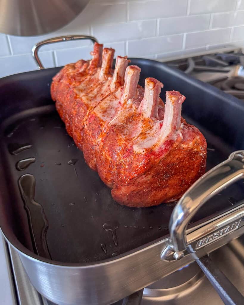 Sear the frenched bone in pork loin roast on each side.