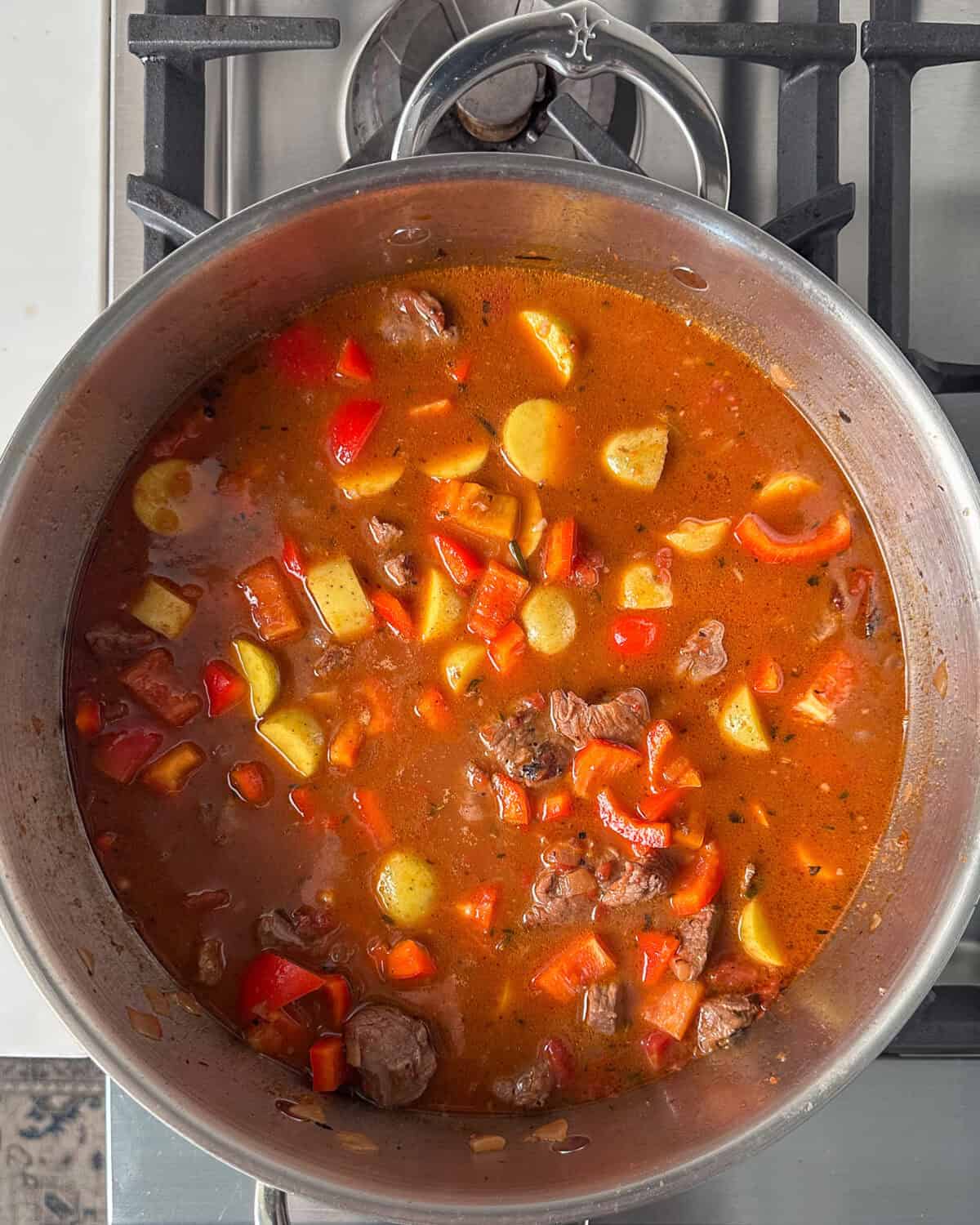 Stir in potatoes and red bell peppers into the spanish style lamb stew.