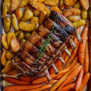 A roasted maple glaze rack of pork served alongside bomba potatoes and citrus orange-glazed carrots.