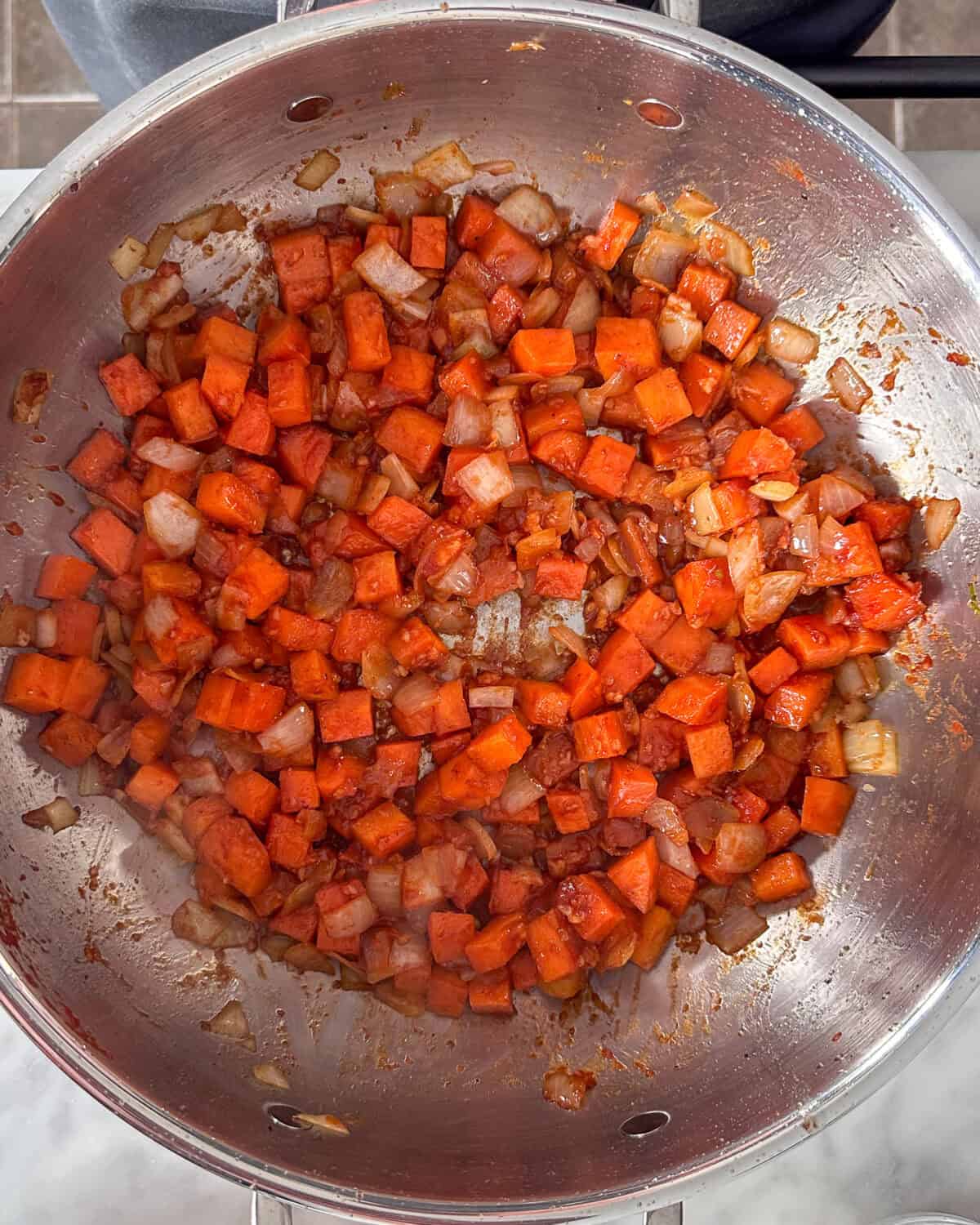 Chopped up onions and carrots in a pan getting sauteed.