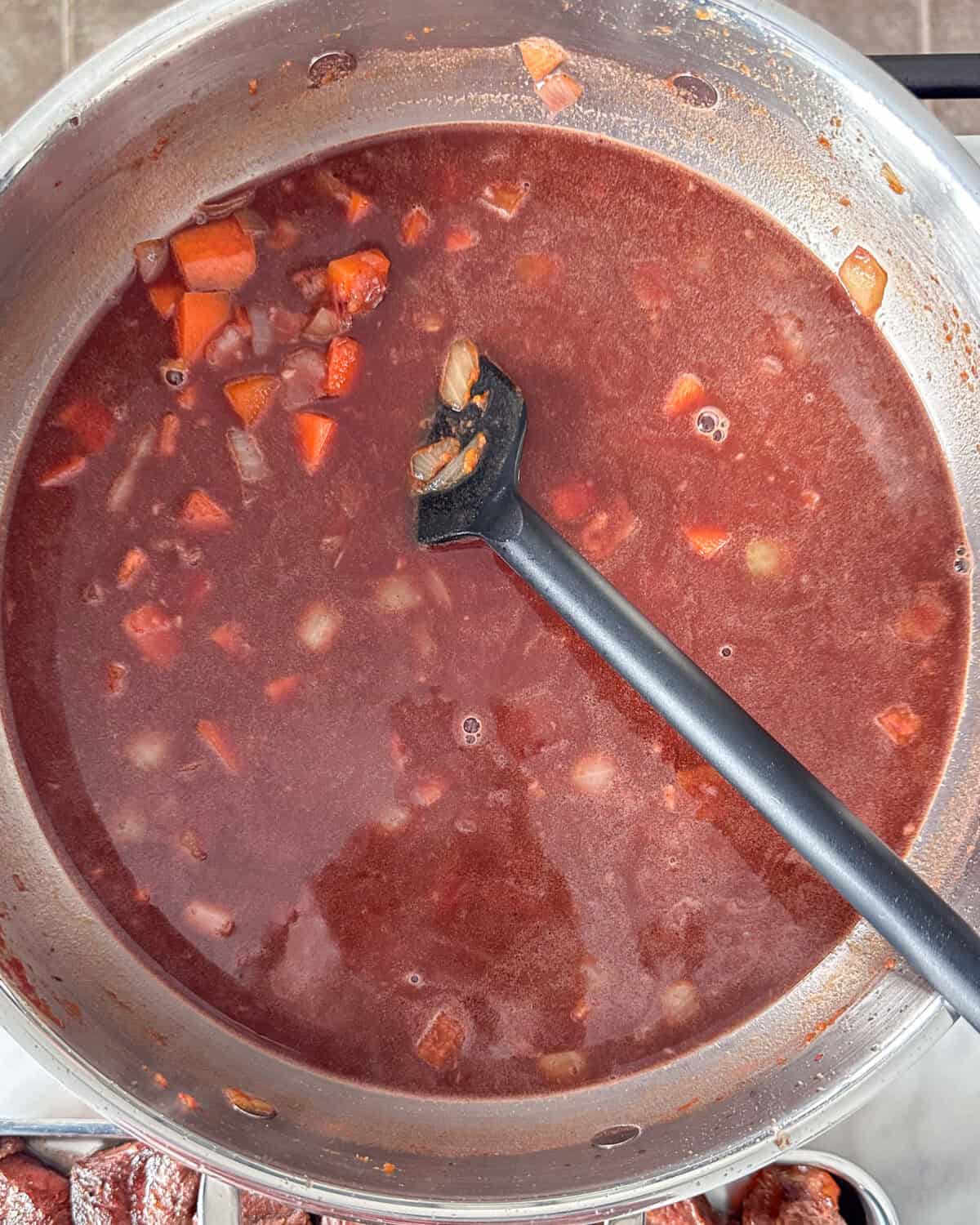 A simmering pot of beef stew with red wine.
