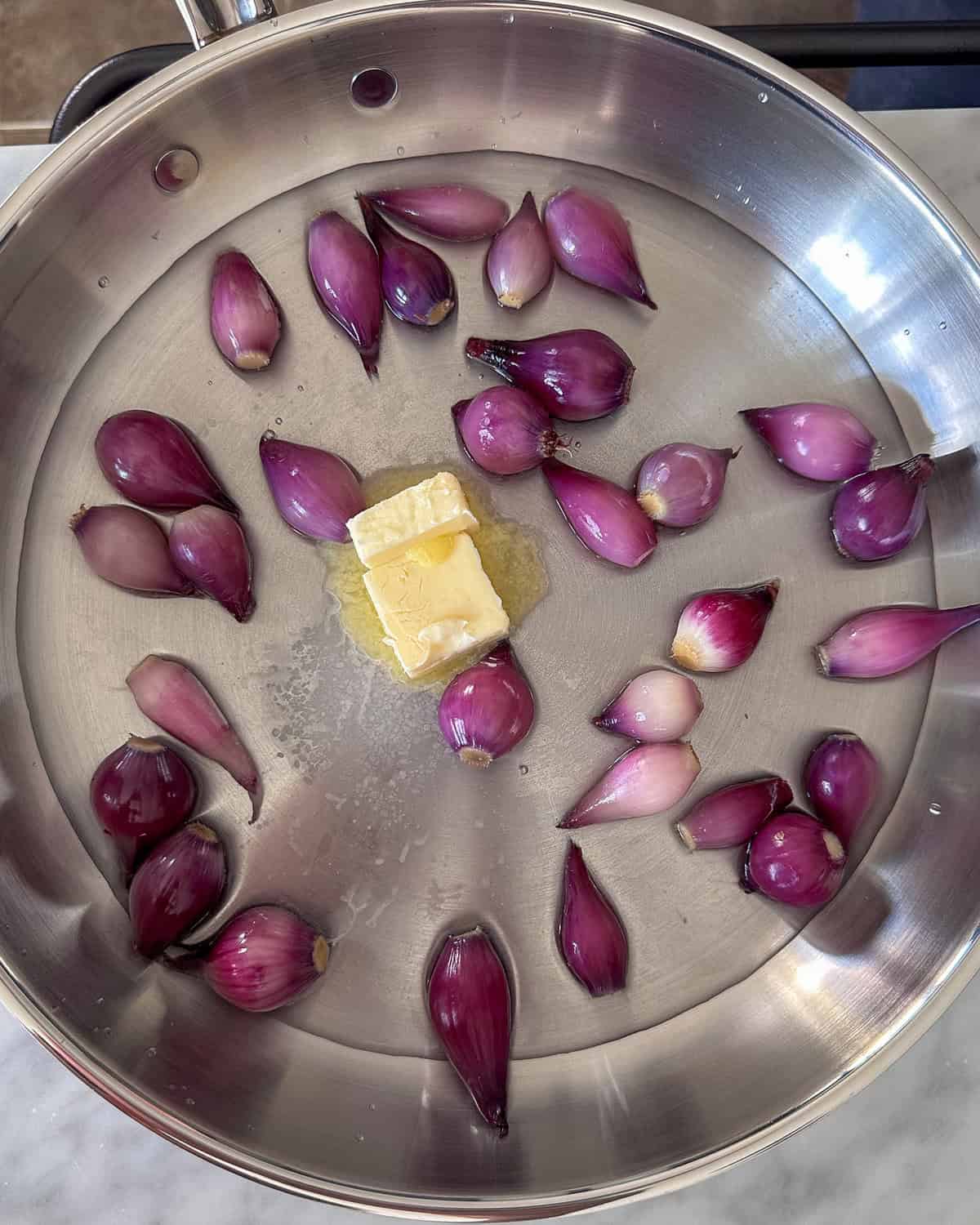 Pearl onions with a knob of butter and water about to get cooked.
