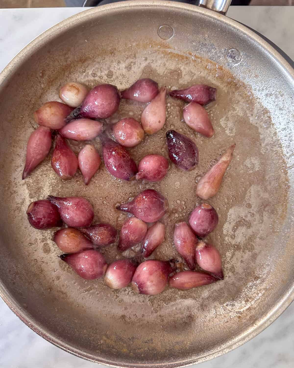 Pearl onions in a pan after they have cooked for 15 minutes.