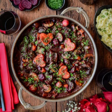 A pot of Beef Bourguignon in a Dutch oven and decorated for a romantic dinner.