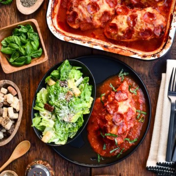 A baking pan with Chicken Pizzaiola with Pepperoni. As well as one plated with a side of Caesar salad.