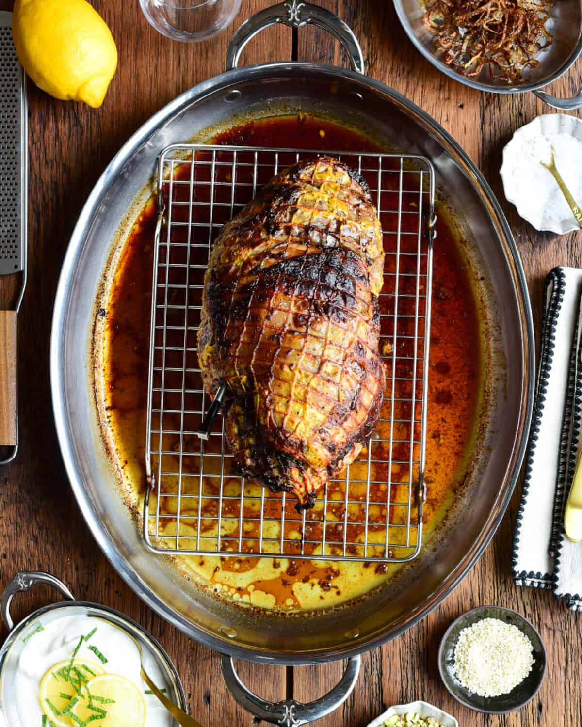 A roasted lamb on a wire rack in a roasting pan.