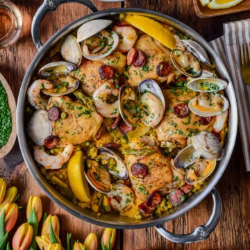 A pot of spring paella mixta with chicken, shrimp. Chorizo and clams.