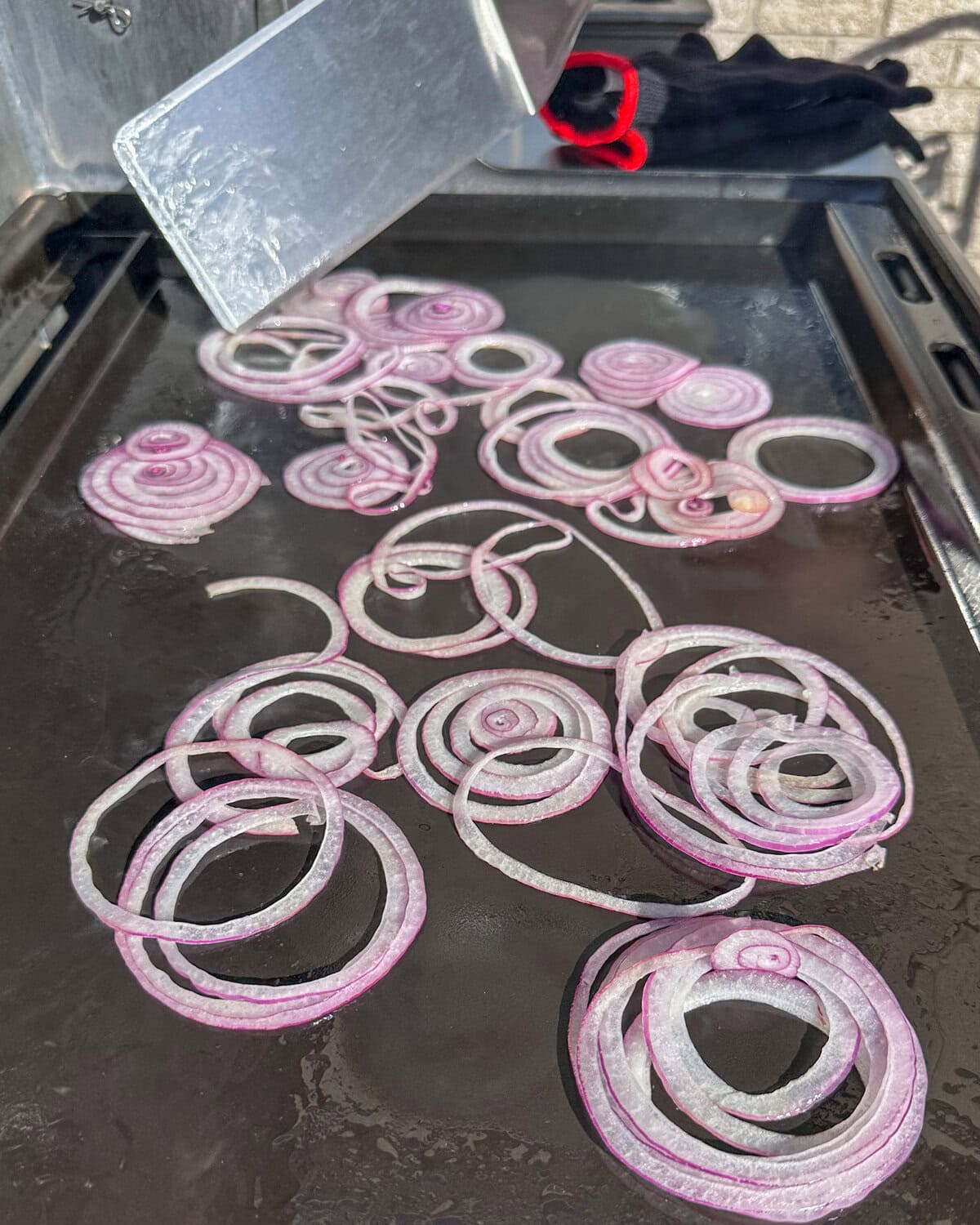 Red onion circles on a griddle.