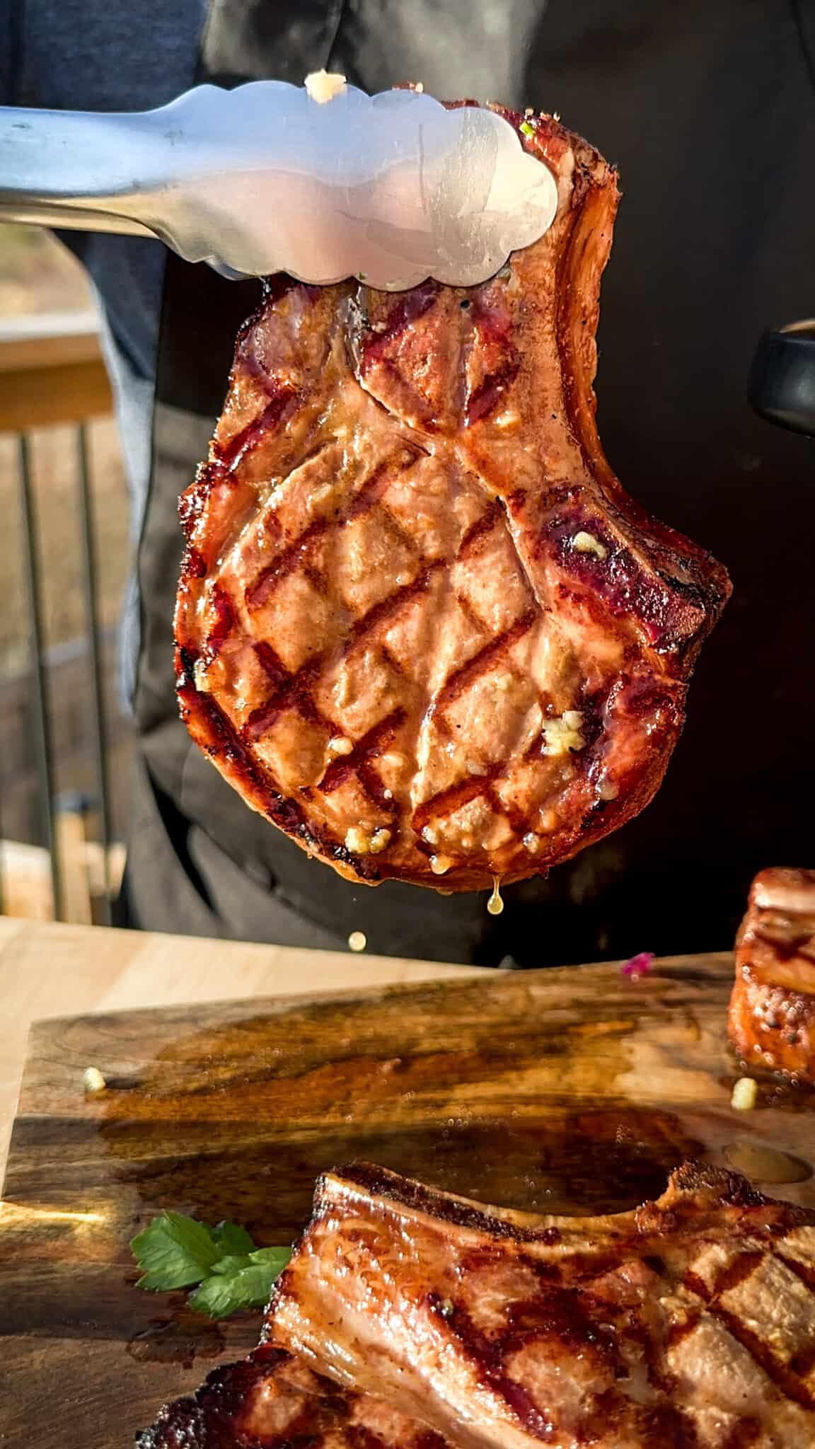 A close-up of a juicy reverse seared pork chop with grill marks.