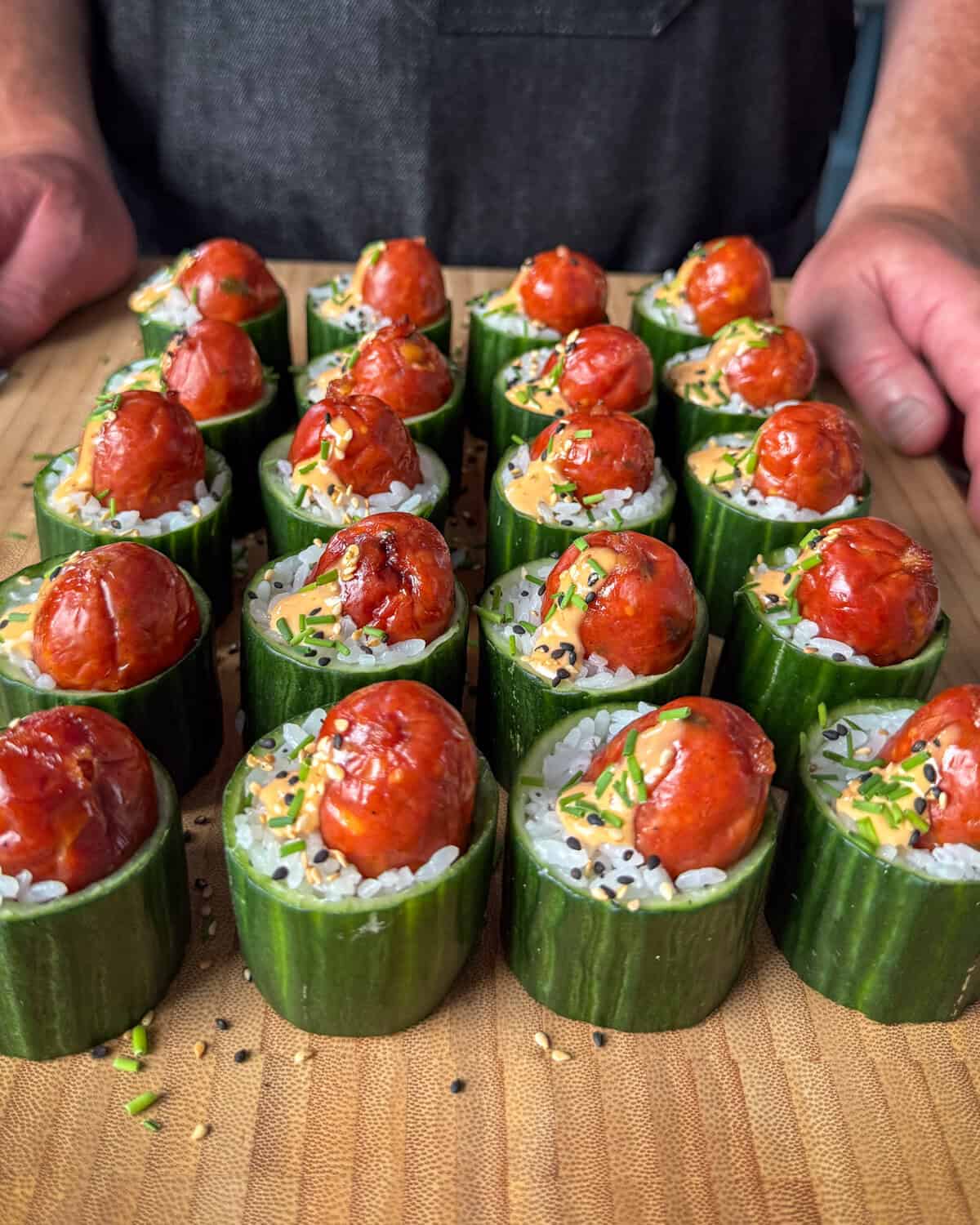 Warm Smokie Popper Sushi Bites in Cucumber Cups in Rows on a cutting board.