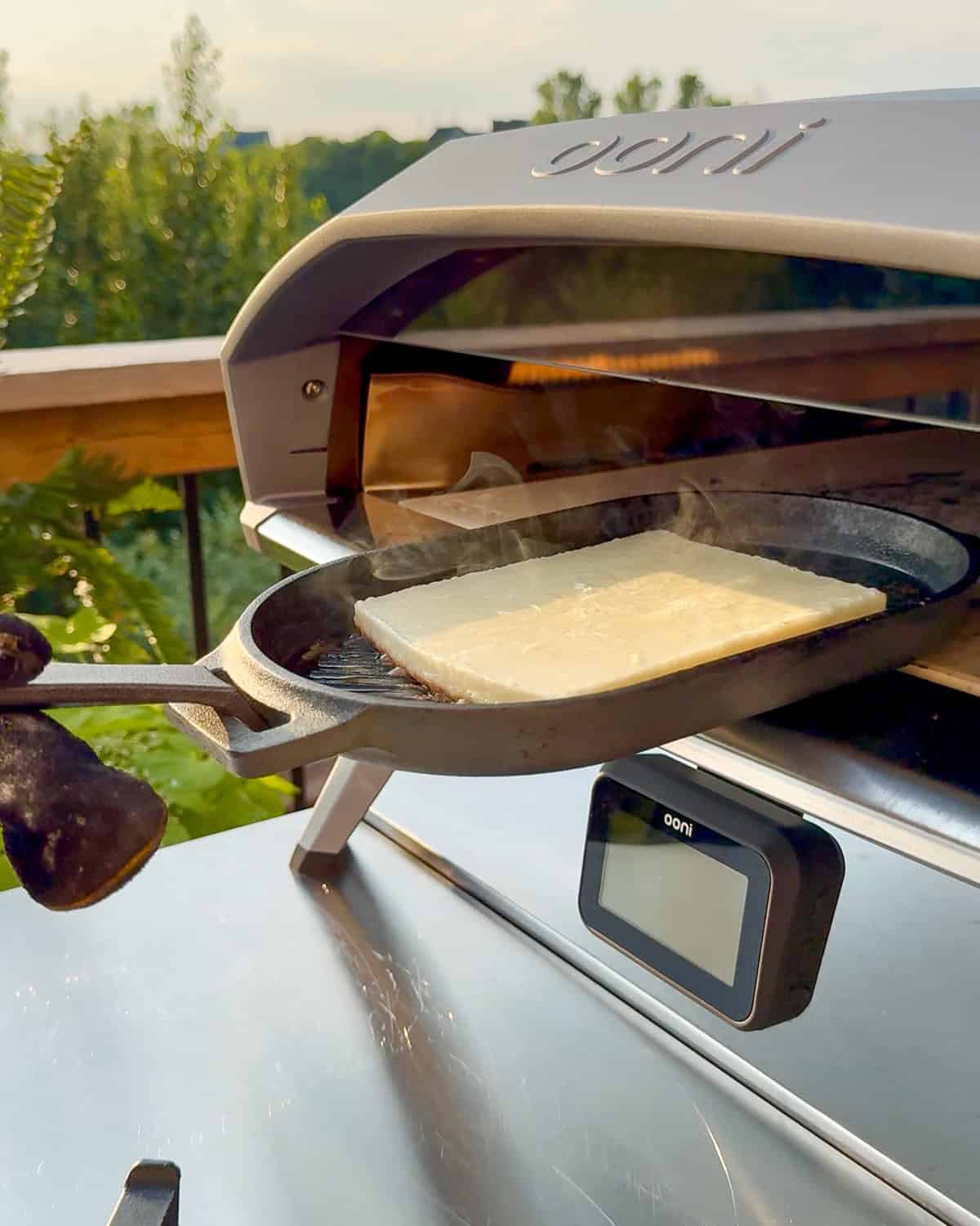 A skillet of Greek fried cheese going into an Ooni oven.