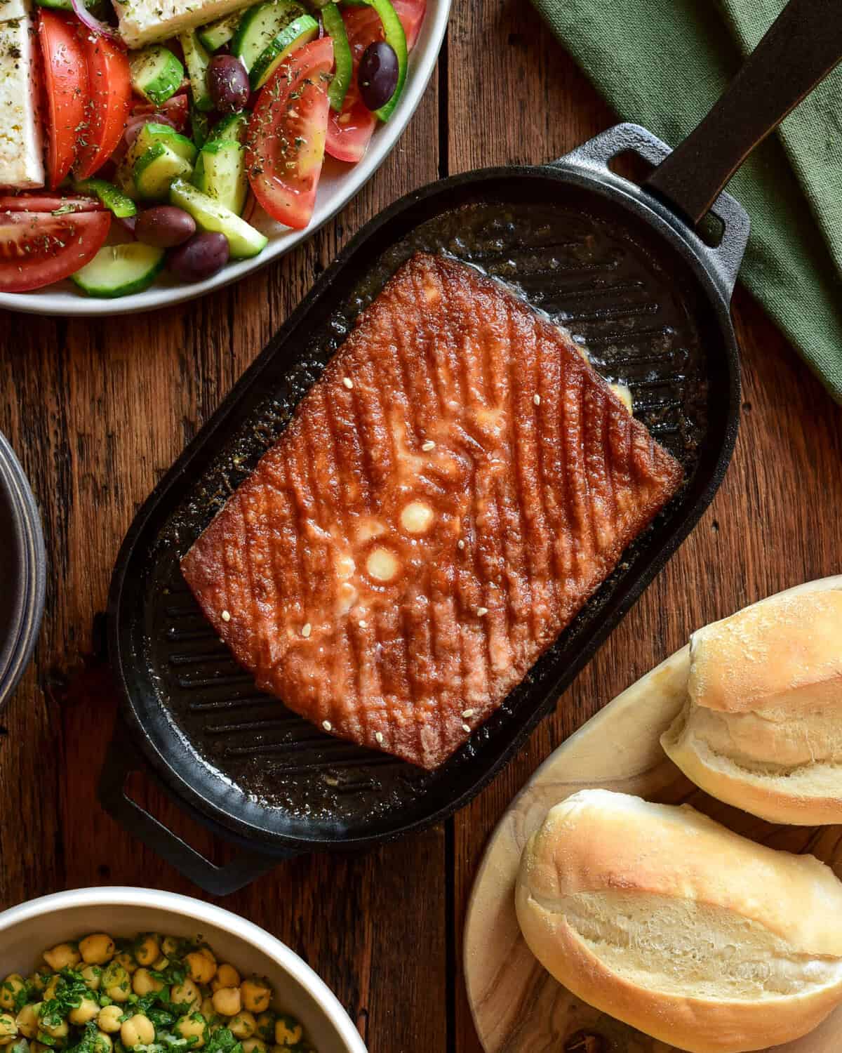Greek kefalotyri cheese in a cast-iron skillet served with a Greek village salad and crusty bread.